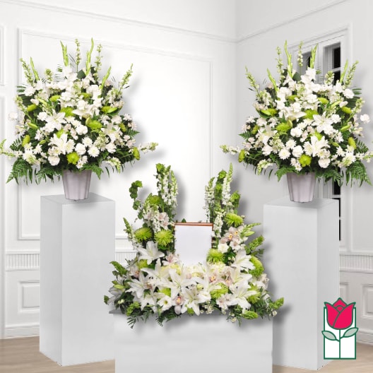 White floral funeral display with lilies and green accents on pedestals