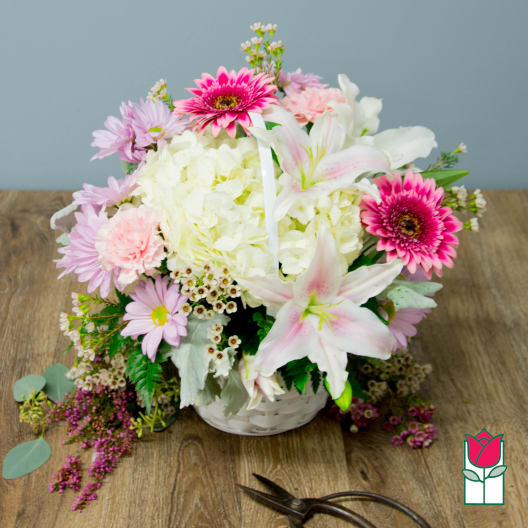 Pink and white mixed flower arrangement in a white basket
