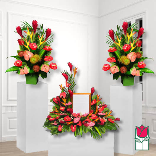 Tropical floral funeral display with red and pink blooms on pedestals