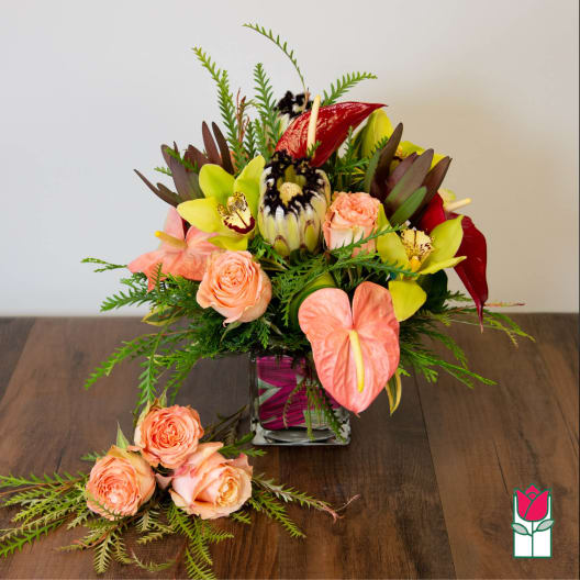 Tropical bouquet in a square glass vase with peach roses and pink anthuriums