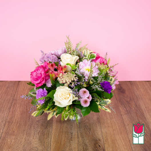 Mixed pink, white, and purple flower arrangement in a clear glass vase