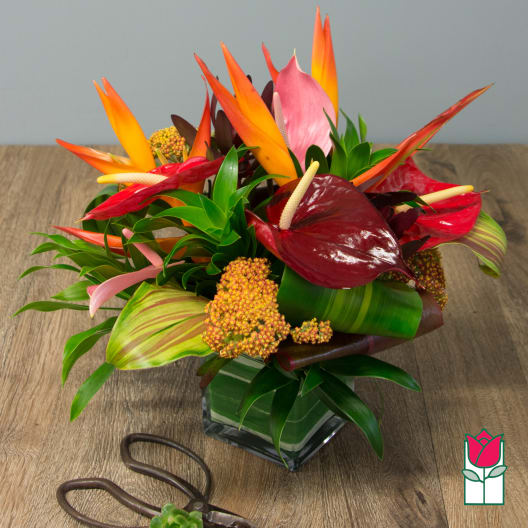 Tropical flower arrangement in a square glass vase