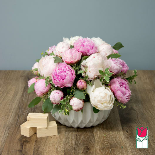 Pink and white peony arrangement in a white bowl vase