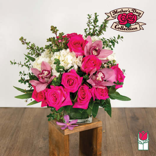 Arrangement of hot pink roses, pink cymbidium orchids, and white hydrangeas in a clear glass vase