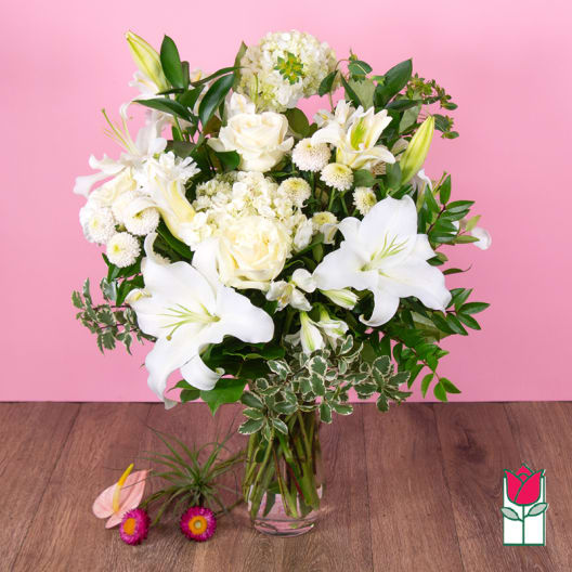 White lilies and roses arranged in a clear glass vase