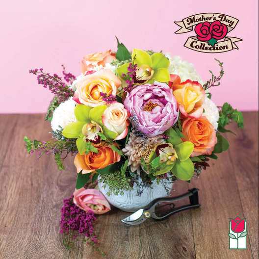 Mixed bouquet of roses, orchids, and a peony in a white vase