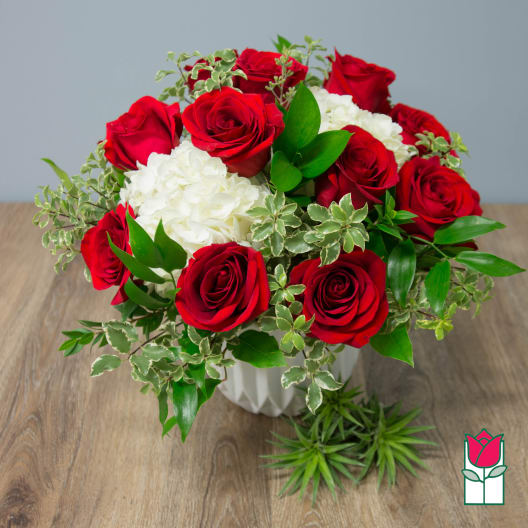 Red roses and white hydrangeas arranged in a white vase