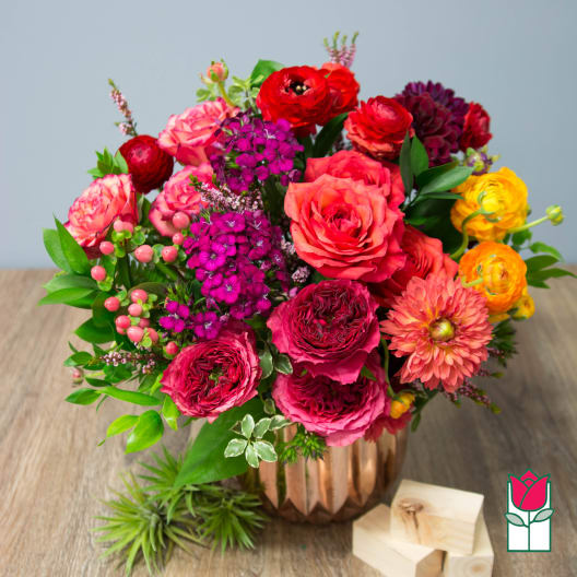 Mixed bouquet of pink, red, and yellow flowers in a copper vase