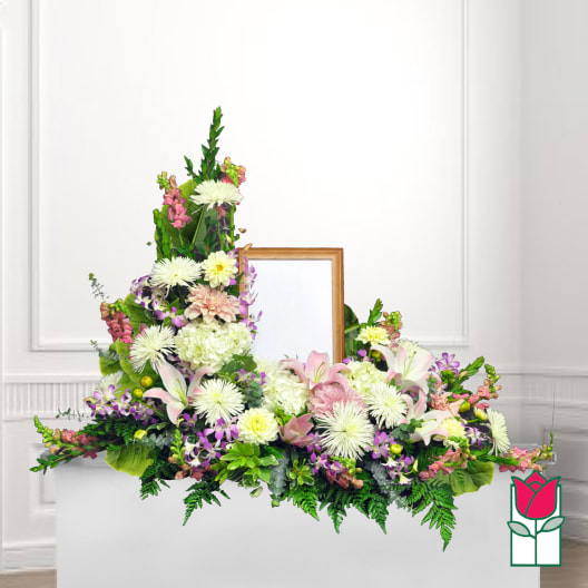 Large floral funeral spray with lilies, chrysanthemums, and pink blooms