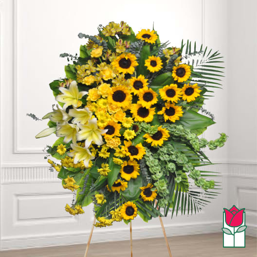 Standing floral spray with sunflowers, lilies, and yellow blooms on an easel