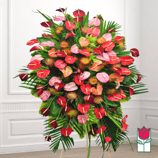 Large standing arrangement of red and pink anthuriums with tropical foliage
