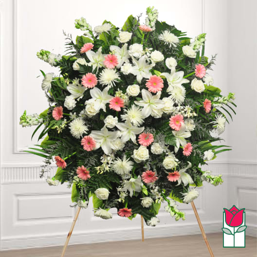 Large standing funeral spray with white and pink flowers on an easel