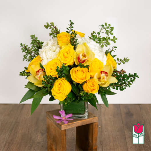 Yellow roses and white orchids in a glass vase