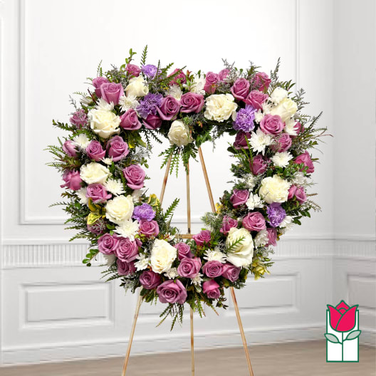 Heart-shaped floral wreath of pink, white, and purple roses on an easel
