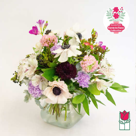 Mixed bouquet of white, pink, and purple flowers in a glass vase
