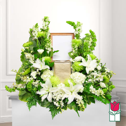 White lilies and green flowers arranged around a framed center and gold box