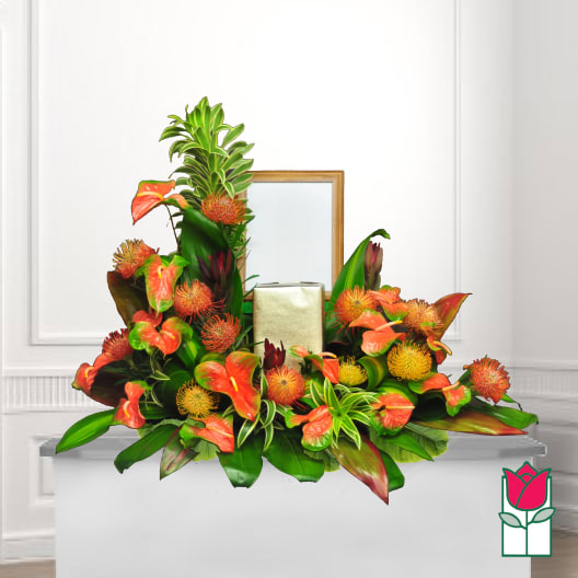 Tropical floral arrangement with orange anthuriums and spiky blooms in a gold container