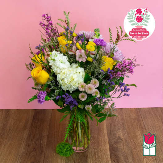 Mixed bouquet of yellow, white, pink, and purple flowers in a glass vase