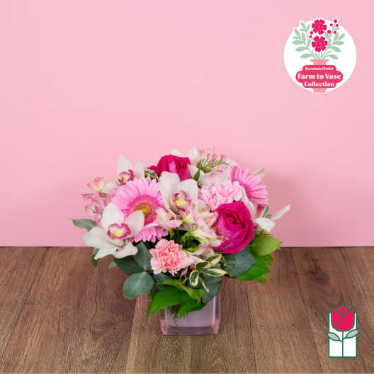 Pink and white mixed flower arrangement in a square glass vase