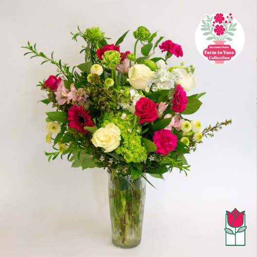 Mixed pink, white, and green flowers arranged in a tall glass vase