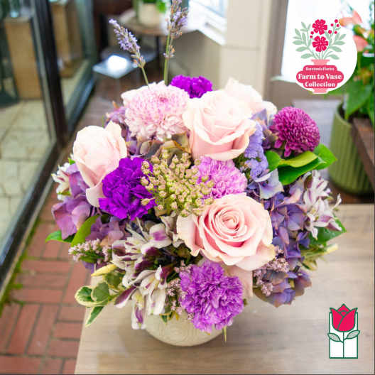 Pink roses and purple mixed flowers arranged in a vase