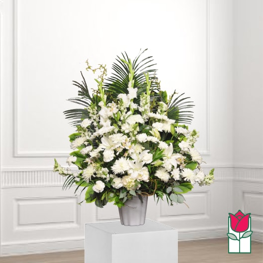 White floral arrangement in a gray vase with palm fronds