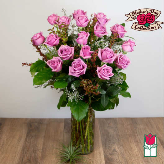 Pink roses arranged in a tall glass vase with greenery.