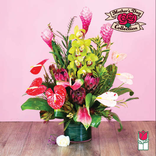 Tropical floral arrangement with pink and red blooms in a green vase