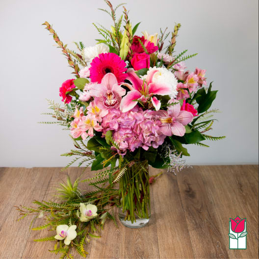 Pink and white mixed bouquet in a clear glass vase with orchids and roses
