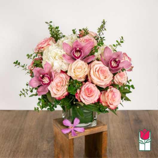Pink roses and orchids arranged in a clear glass vase