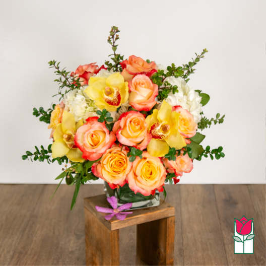 Bouquet of yellow and peach roses with orchids in a glass vase