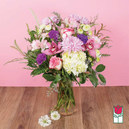 Mixed pink, white, and purple flowers in a clear glass vase