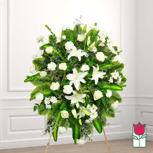 Large white funeral spray with lilies, roses, and daisies on a stand