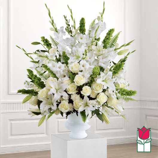 White floral arrangement in a white vase with green accents