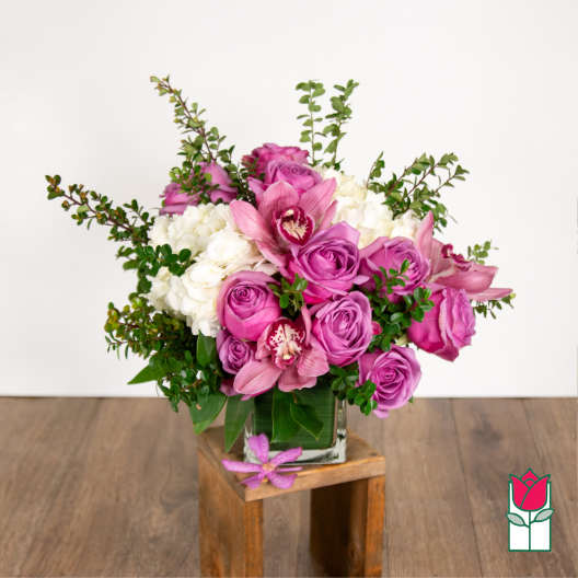 Pink roses and orchids arranged in a clear glass vase