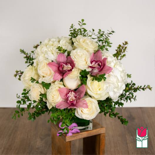 White roses and hydrangeas with pink orchids in a glass vase