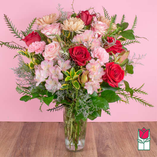 Bouquet of red and pink roses with pale blooms in a clear glass vase
