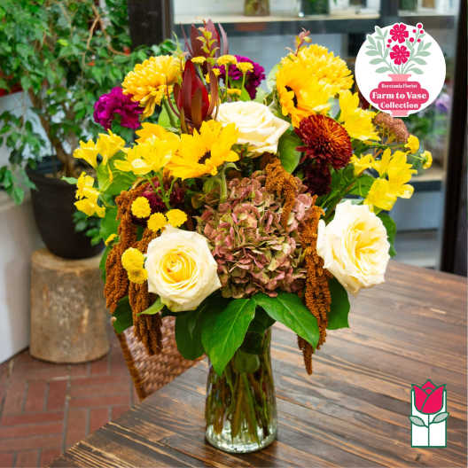 Mixed bouquet of yellow, white, and burgundy flowers in a glass vase