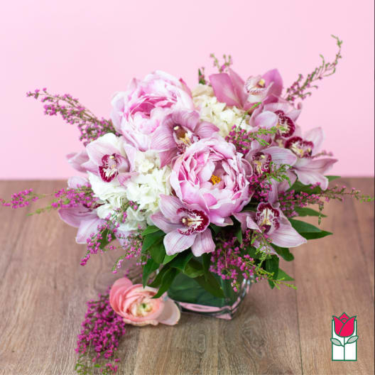 Pink peonies and orchids arranged in a glass vase