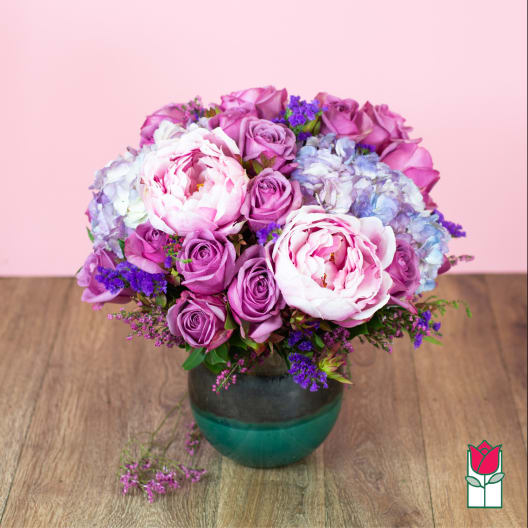 Pink and purple bouquet of roses and peonies in a glass vase