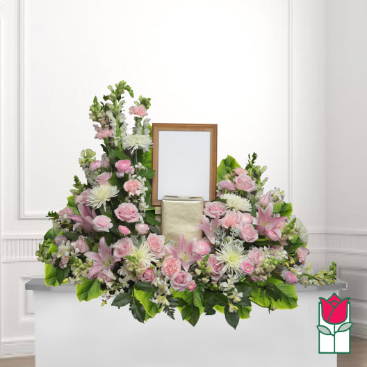 Pink and white floral funeral tribute around a framed photo