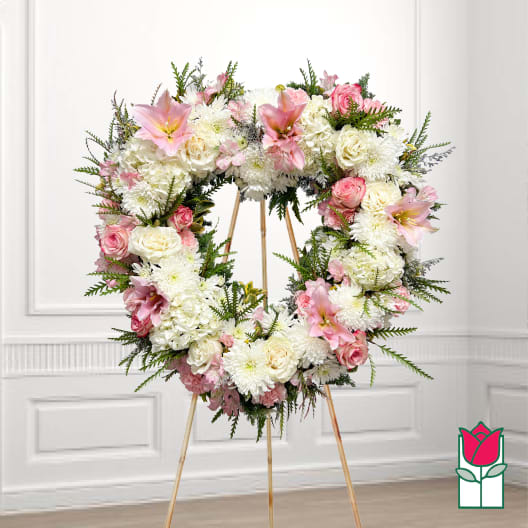Heart-shaped floral wreath on a stand with pink and white flowers