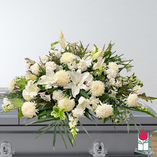 White floral casket spray with lilies and pompons