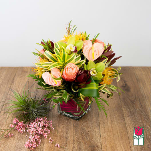 Tropical bouquet in a glass vase with pink anthuriums and orchids