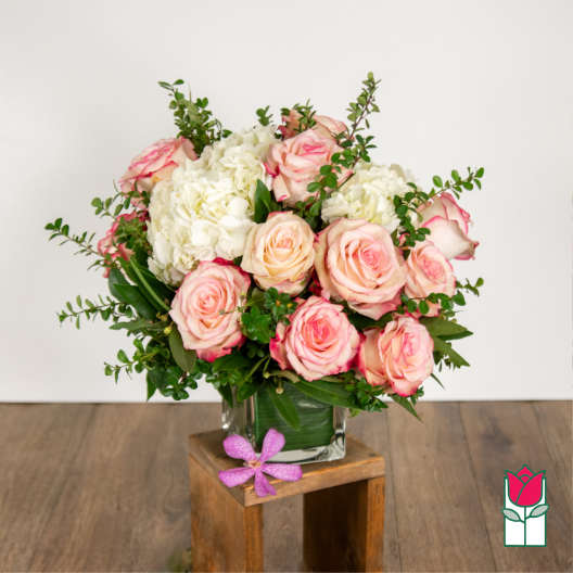 Pink roses and white hydrangeas in a clear glass vase.
