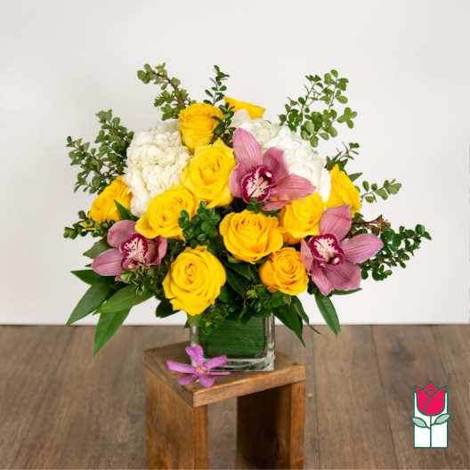 Yellow roses and pink orchids in a glass vase