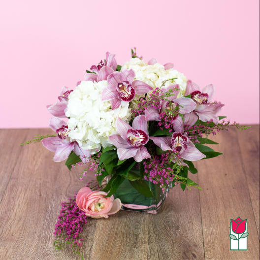 Pink orchids and white hydrangeas arranged in a glass vase