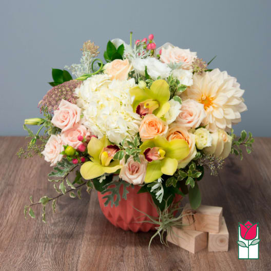Mixed bouquet in a coral vase with pale roses and yellow orchids