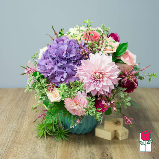 Bouquet of purple, pink, and cream flowers in a teal vase