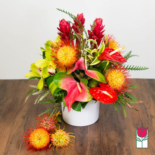 Tropical flower arrangement in a white vase with red and yellow blooms